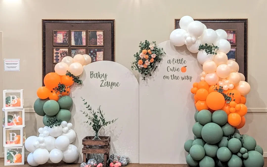 a little peach on the way baby shower photo booth - white orange and sage green balloon arch , custom wood arches , floral arrangement